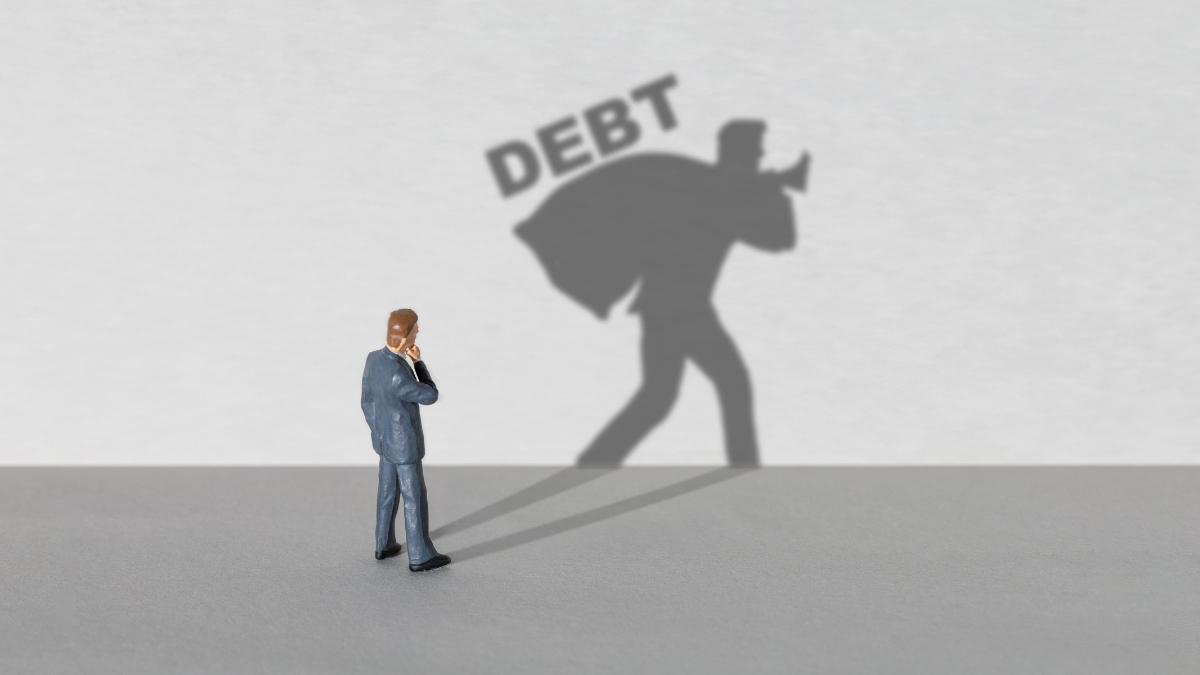 Businessman confronting debt burden, symbolizing financial stress, debt management, loan repayment, personal finance, and financial planning.