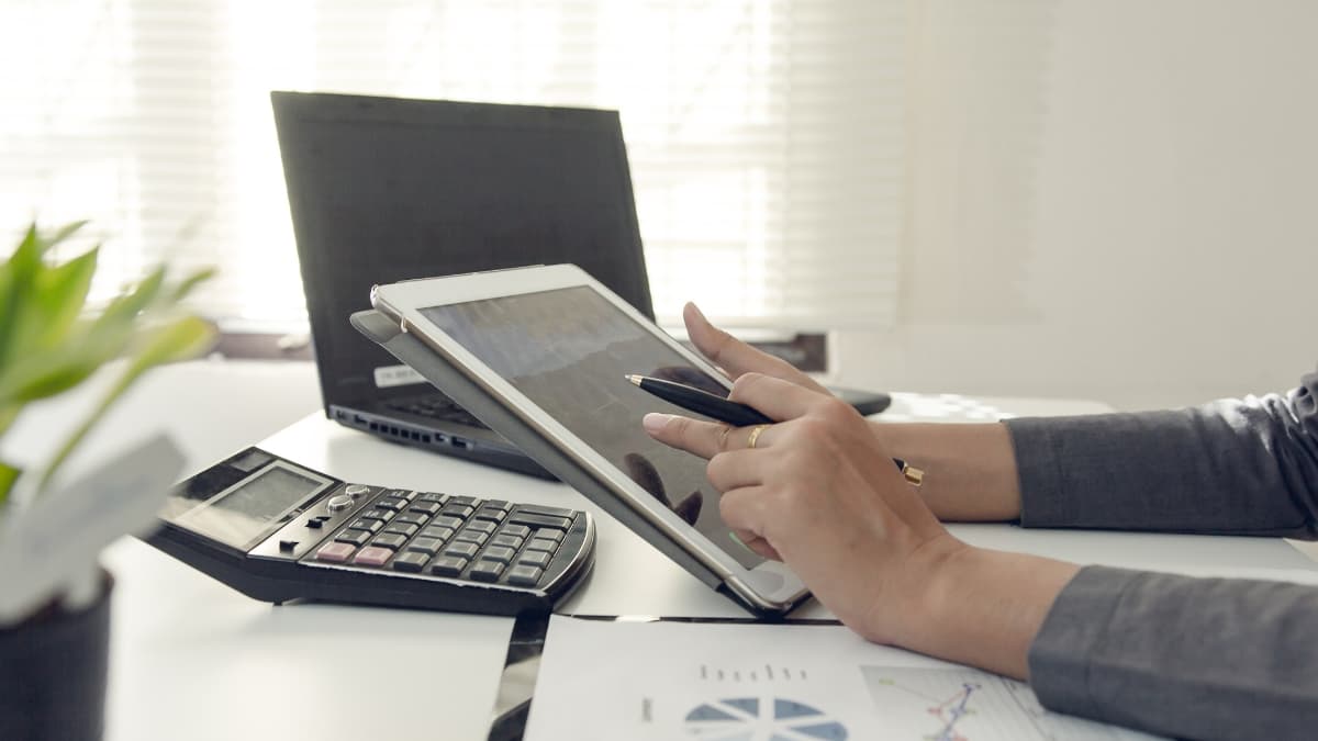 Person using a tablet and calculator at a desk to compare mortgage refinance rates online.