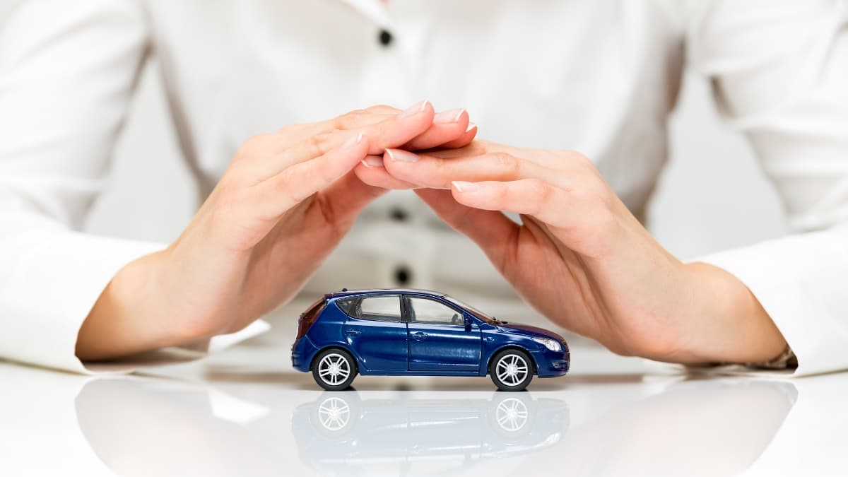 Hands covering a small blue car to symbolize Complete Car Warranty protection and vehicle coverage
